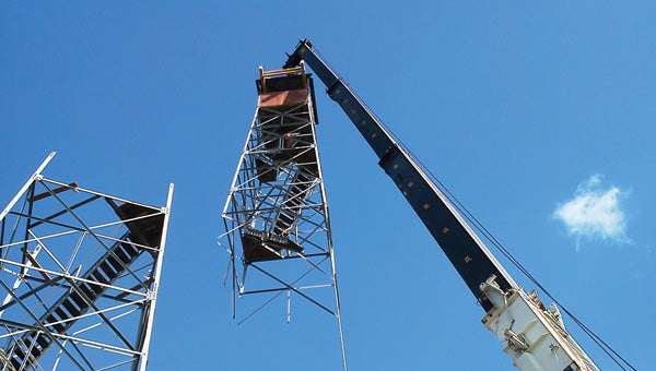 A crane lifts the partially-dismantled fire tower from its perch.  The tower will be transported to New York for restoration.