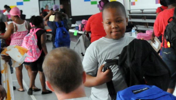 Alabama Power Company’s Rod Cater gives Greenville Elementary School student Dontavious Adams a backpack during Saturday’s bookbag giveaway. (Advocate Staff/Andy Brown)