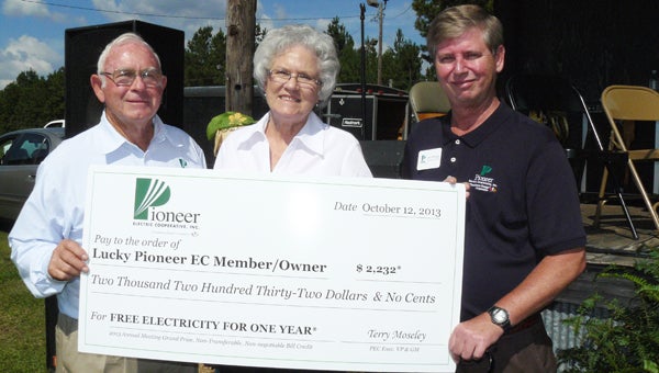Pioneer Electric Cooperative Executive Vice President and General Manager Terry Moseley (left) and Pioneer Electric District 2 Carey Thompson (right) present the annual meeting’s top prize, free electricity for one year, to June Whittle of Georgiana. She receives a $2,232 bill credit. (Courtesy Photo)