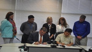 Crenshaw County Schools Superintendent Randy Wilkes, front left, signs an agreement with Smart Alabama vice president Hug Heo, front right, to provide teachers for the new career technical center.