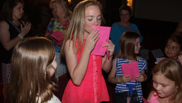 Abbie Salter puts pinkalicious lip prints on programs presented by young fans after Friday night’s show. (Photo by Angie Long)