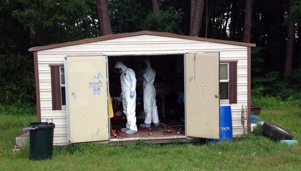 Officers with the Second Judicial Drug Task Force search a utility shed that was being used as a meth lab. The lab was found at a home on North Street in McKenzie. (Courtesy Photo)