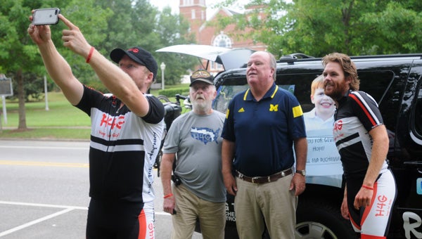 Greenville Mayor Dexter McLendon poses for a photo with Michael Staley, front, Glenn Nevansm, left, and Wes Bates, right, during the team’s stop in the Camellia City. The cyclists are riding cross-country to raise awareness about Duchenne Muscular Dystrophy. (Advocate Staff/Andy Brown)