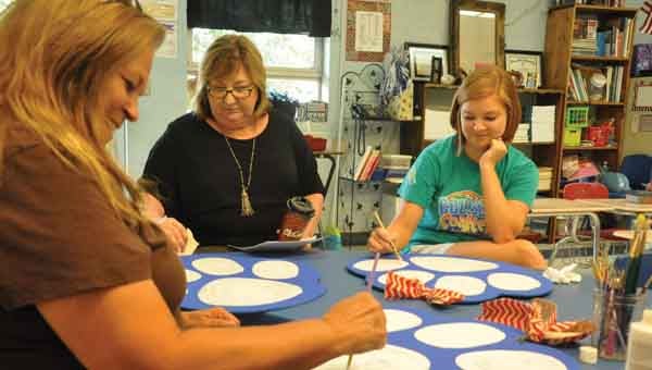  JOURNAL PHOTO | MONA MOORE Crenshaw Christian Academy’s Debbie Christian, Angela Carpenter and Amber McInvale paint signs for classroom doors. 