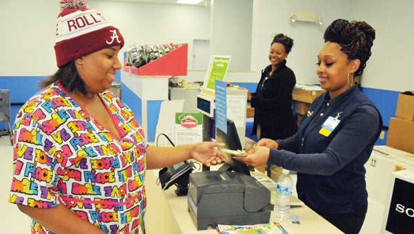Walmart cashier Iesha McCall (right) performs a transaction for customer Rakema Lee Tuesday afternoon at the Greenville store.