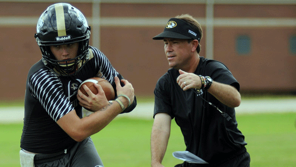 Greenville High School head coach Josh McLendon works on ball security with senior quarterback Brandon Simmons Monday during the opening of fall camp for the Tigers.