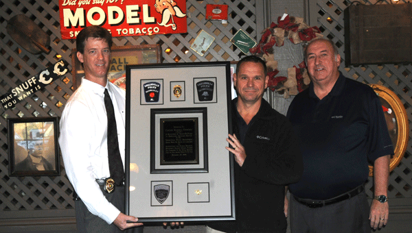 Greenville Police Chief Justin Lovvorn, left, and retired GPD chief Lonzo Ingram, right, honor Capt. Randal Courtney with a plaque for his 25 years of service to the department at his retirement breakfast held Friday.   